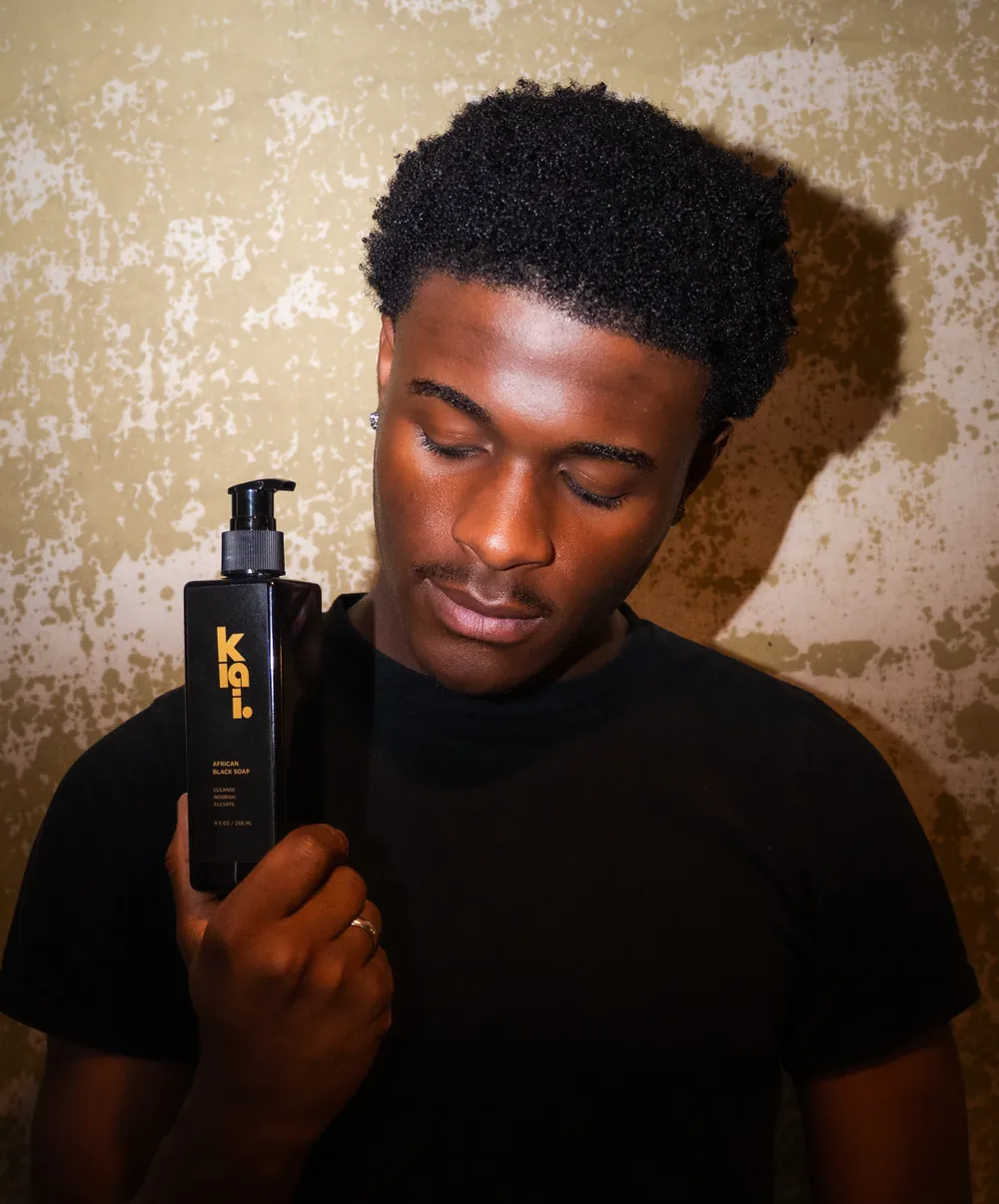 A man holding the klai. African Liquid Black Soap bottle
